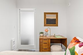 a bedroom with a bed and a desk and a door to a bathroom at Hue Apartments, Washington, 98052