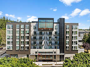 an aerial view of a building with a glass facade and trees at Hue Apartments, Washington