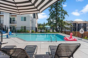 A pool with a red float and a striped umbrella.