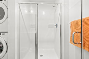 a bathroom with a shower and a washing machine at Hue Apartments, Redmond , 98052