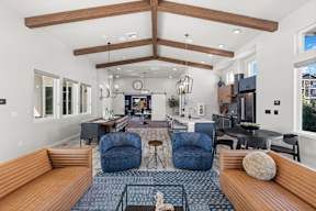 A modern living room with a large wooden beam ceiling and a variety of seating options.