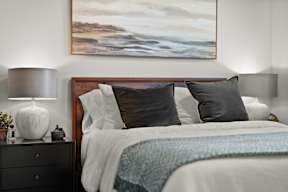 A bedroom with a large bed and a painting above it.
