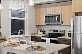 A modern kitchen with a stainless steel refrigerator, microwave, and oven.