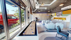 A room with a red car outside the window and a pool table.