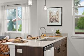 A kitchen with a white countertop and a framed picture hanging above the sink.