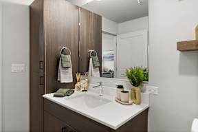 A bathroom with a white counter top and a brown cabinet.