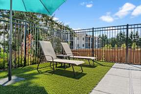 A sunny day at the park with two chairs and a table under a green umbrella.