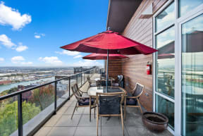 a balcony with a table and chairs and a red umbrella