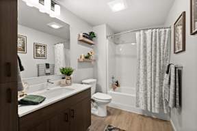 A bathroom with a white toilet, sink, and shower curtain.