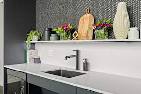 a kitchen with a sink and a shelf with vases and flowers at Hue Apartments, Redmond , WA 98052