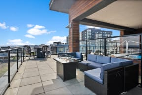 a rooftop terrace with couches and tables and a view of the city