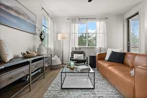 A living room with a brown leather couch, a coffee table, and a painting on the wall.