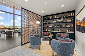 a living room with blue chairs and a table and a large window at Hue Apartments, Redmond