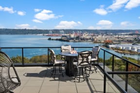 a balcony with a table and chairs overlooking the water and a city