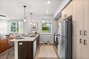 A modern kitchen with a refrigerator, sink, and dining table.