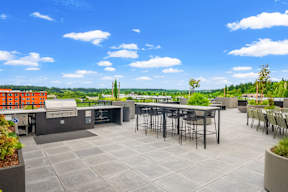 a rooftop patio with tables and chairs and a grill at Hue Apartments, Washington, 98052