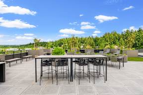 a rooftop patio with tables and chairs and a view of trees at Hue Apartments, Redmond