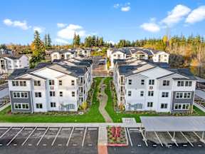 A row of white houses with a parking lot in front.