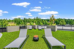 a group of gray lounge chairs on a green lawn at Hue Apartments, Redmond , WA 98052
