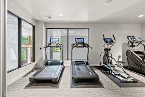 two treadmills and other exercise equipment in a gym with glass doors at Hue Apartments, Washington, 98052