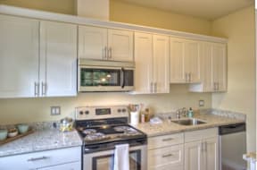 A kitchen with a stove, microwave, and cabinets.