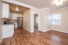 A kitchen with white cabinets and a wooden floor.