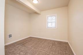 A room with a window and carpeted floor.