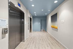 a hallway with elevators and a painting in a building at Hue Apartments, Washington
