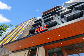 the facade of a hhc building with a red sign on top at Hue Apartments, Redmond , WA