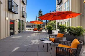 A patio with orange chairs and umbrellas.