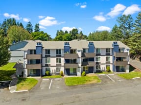 an aerial view of an apartment building with a parking lot and grass