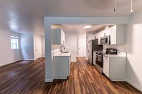 A kitchen with white cabinets and a wood floor.