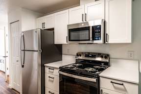 A black fridge and microwave in a white kitchen.