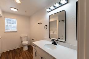 A bathroom with a toilet, sink, and mirror.