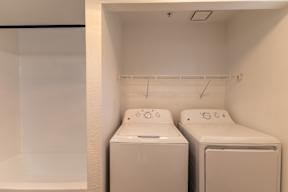 Two white front loading washing machines in a small laundry room.