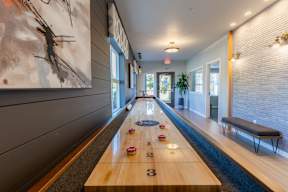 A long room with a shuffleboard table in the middle.