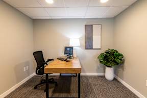 A room with a desk, chair, and computer.