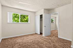 an empty bedroom with a closet and a window
