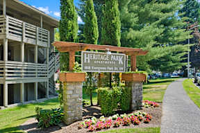 a sign for heritage park apartments in front of a sidewalk