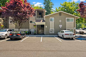 a parking lot with cars in front of an apartment building