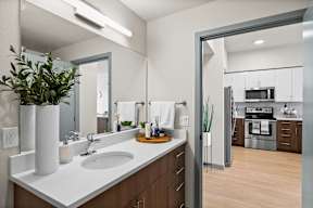a kitchen with white counters and a sink and a mirror