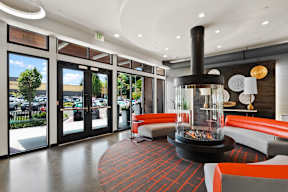 the lobby of a hotel with a fireplace and orange chairs