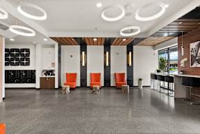 a large lobby with orange chairs and a bar and white walls