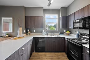 an updated kitchen with black appliances and white countertops