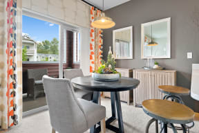 a living room with a table and chairs and a balcony