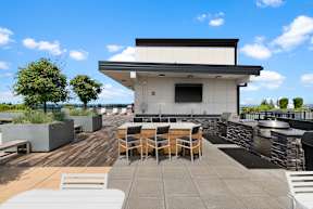 a patio with tables and chairs and a grill on a roof