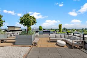 a roof top patio with couches and tables and views of the city