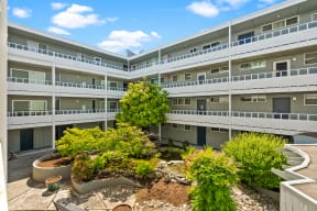 an exterior view of an apartment building with trees in the courtyard