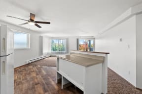 an empty living room with a kitchen and a ceiling fan