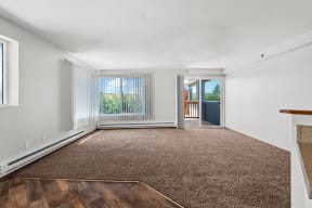 an empty living room with a rug and a door to a balcony